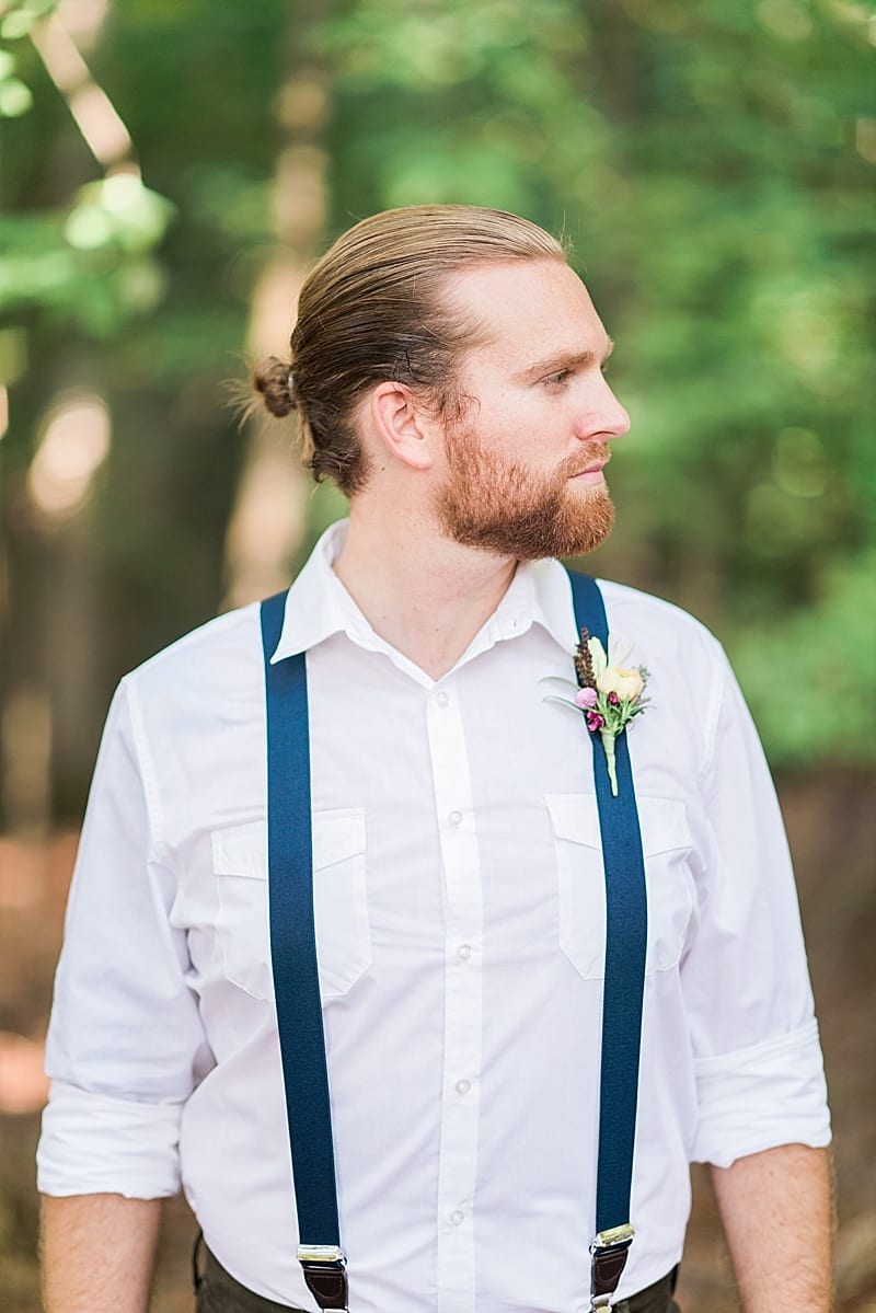 groom in suspenders with man bun