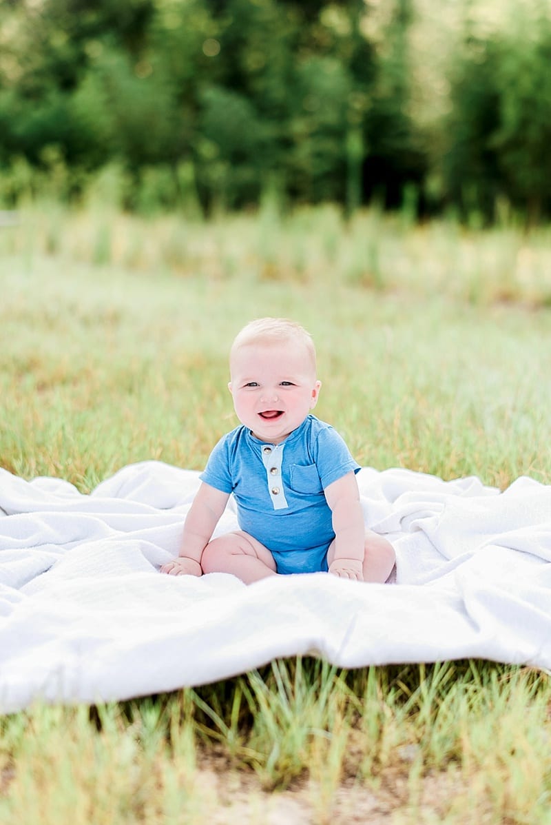 six month old boy with blue eyes sitting on a blanket photo