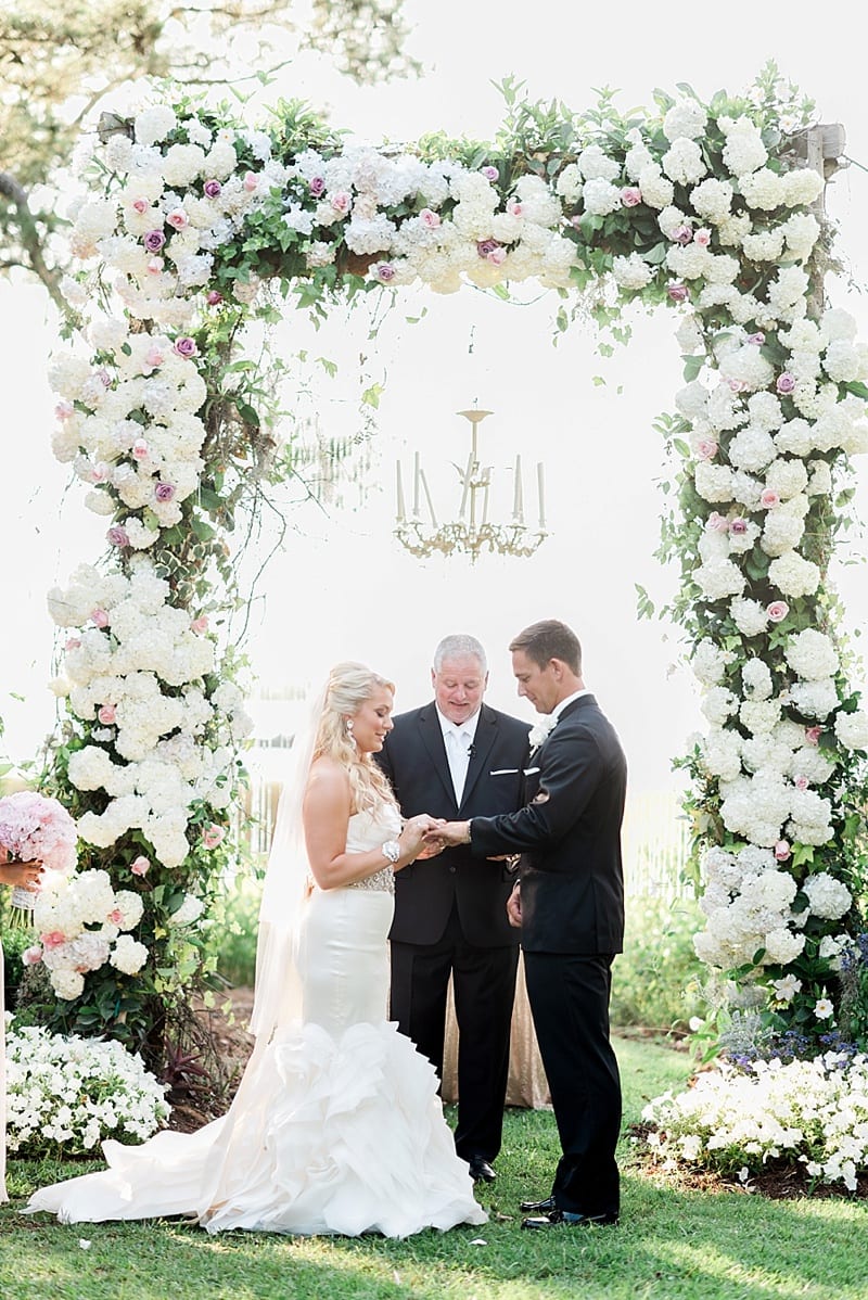 wedding ceremony ring exchange in front of floral arbor photo