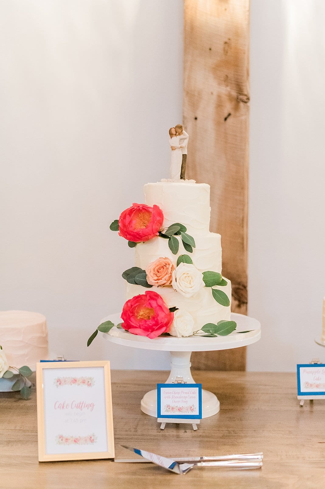 Maxie B's 3 tiered wedding caked with bright coral flowers and greenery photo