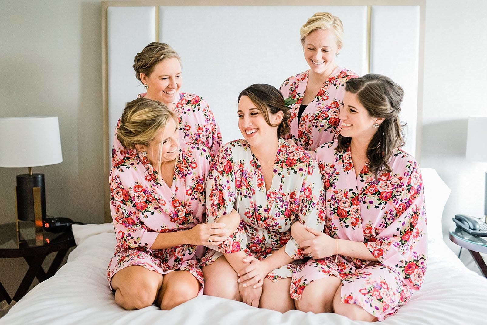 downtown raleigh wedding bridesmaids in robes on bed with bride photo