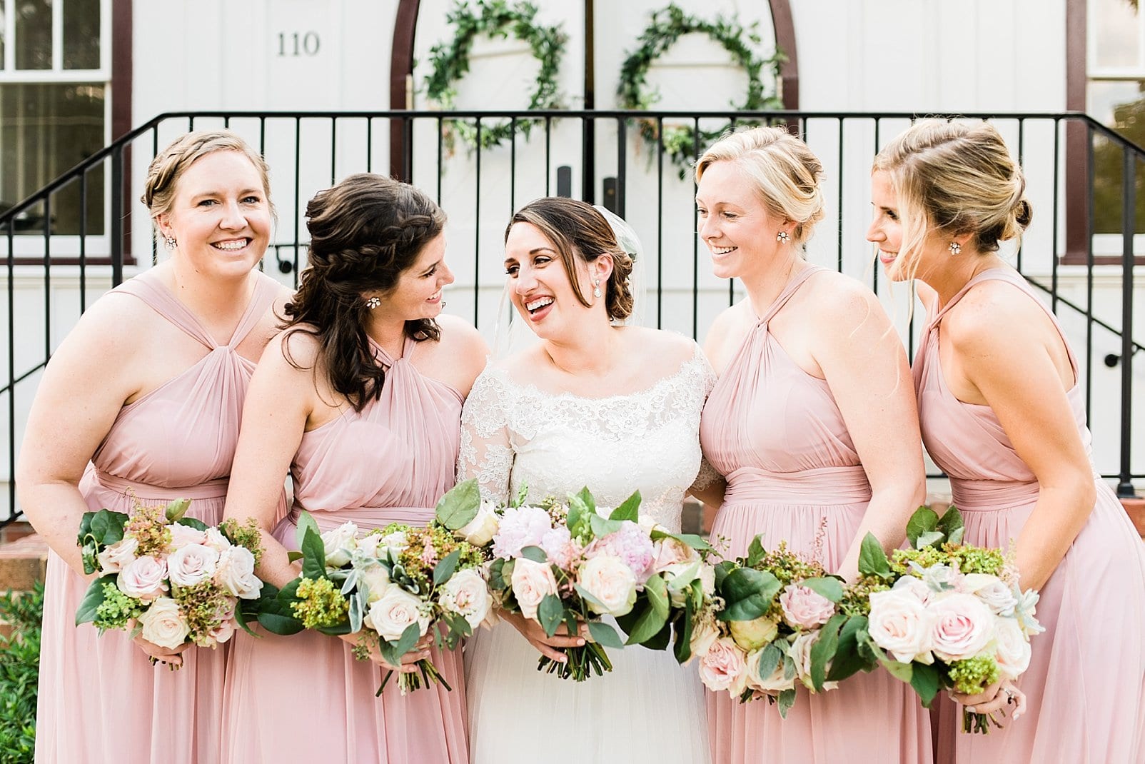 downtown raleigh wedding bride laughing with bridesmaids in light pink long gowns photo