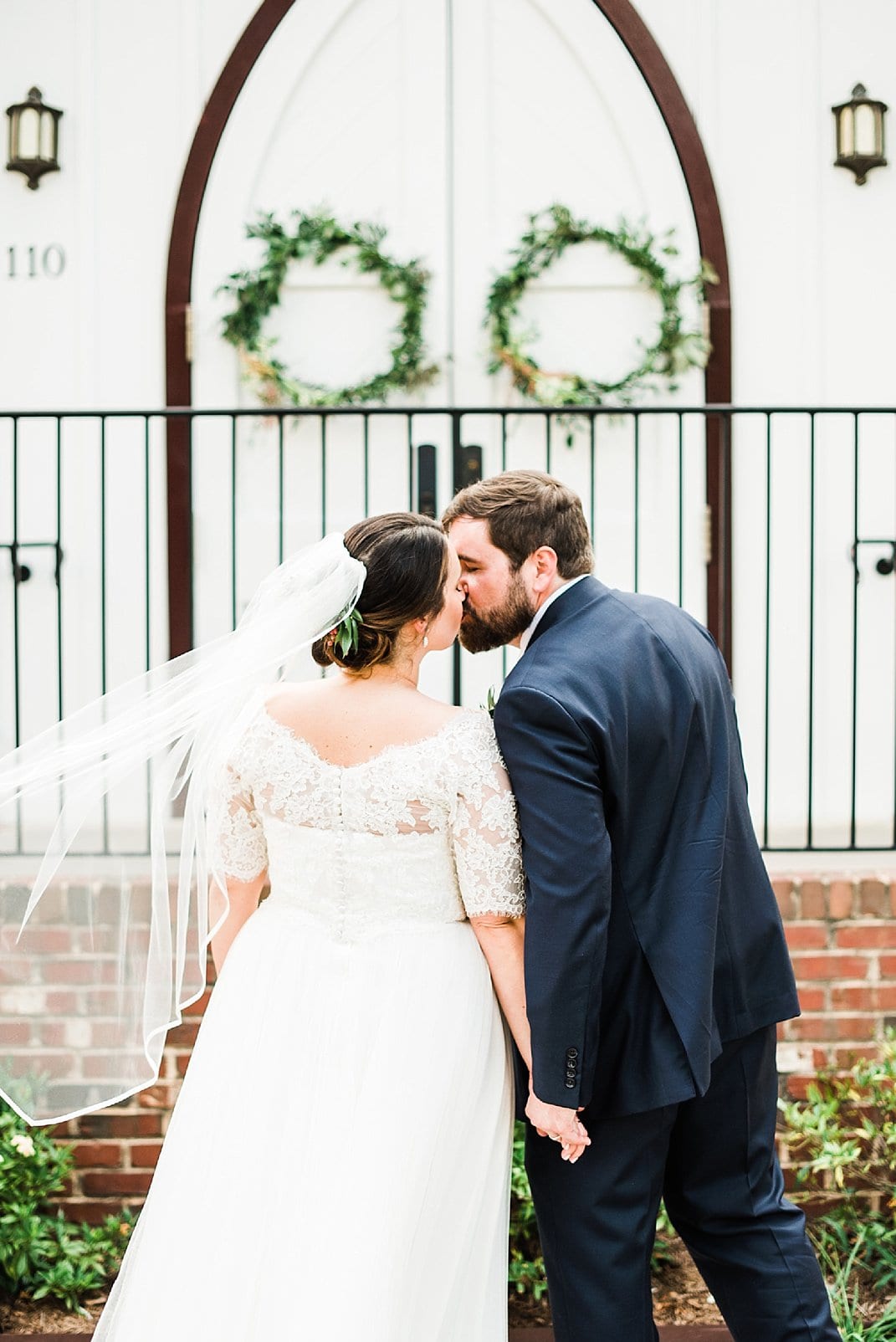 downtown raleigh wedding bride and groom kissing with veil blowing in the wind photo