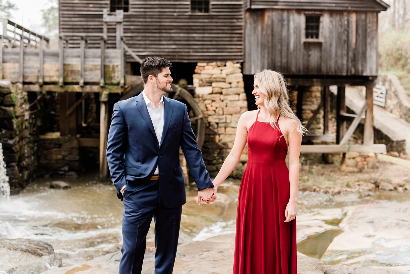 Raleigh engagement session couple holding hands in front of old mill building photo