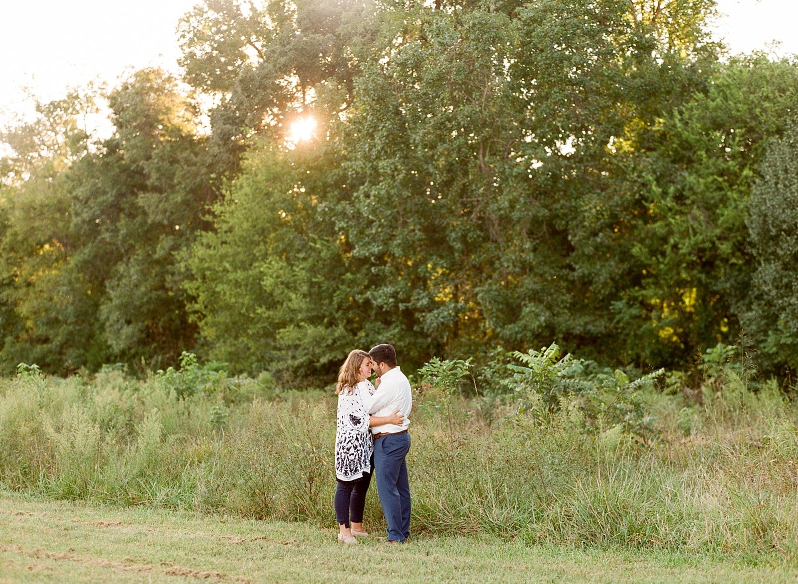 nc engaged couple snuggling in a field at sunset photo