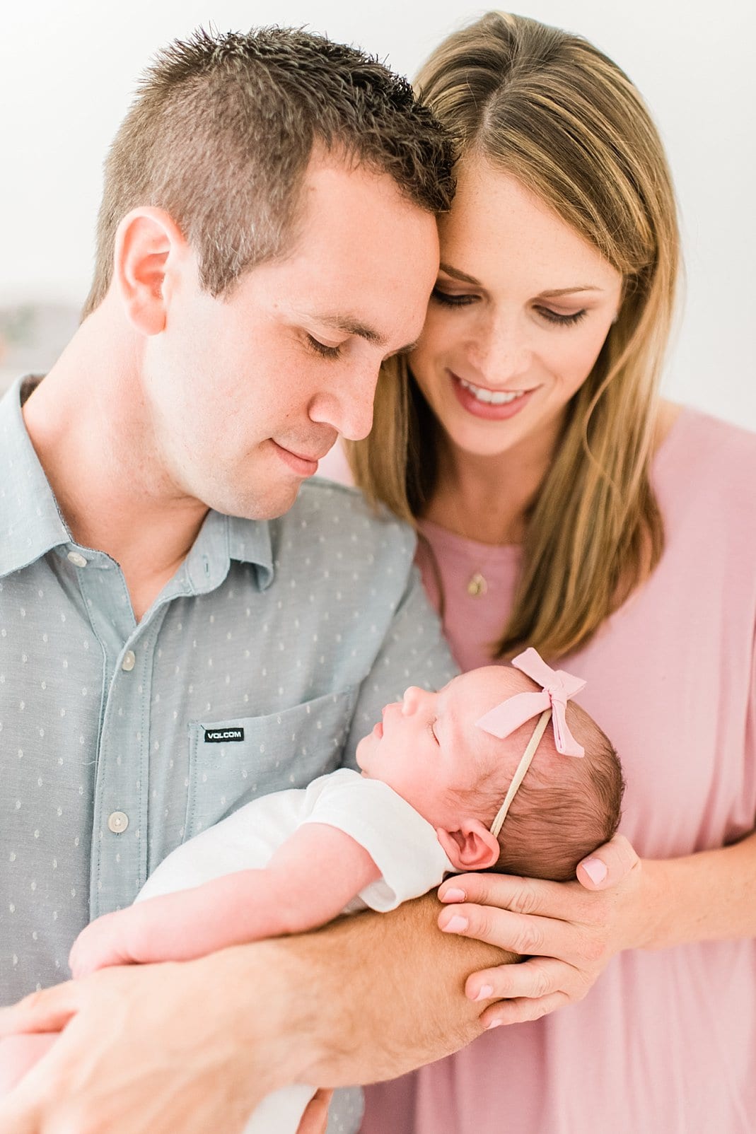 raleigh parents holding newborn girl with a tiny bow headband photo