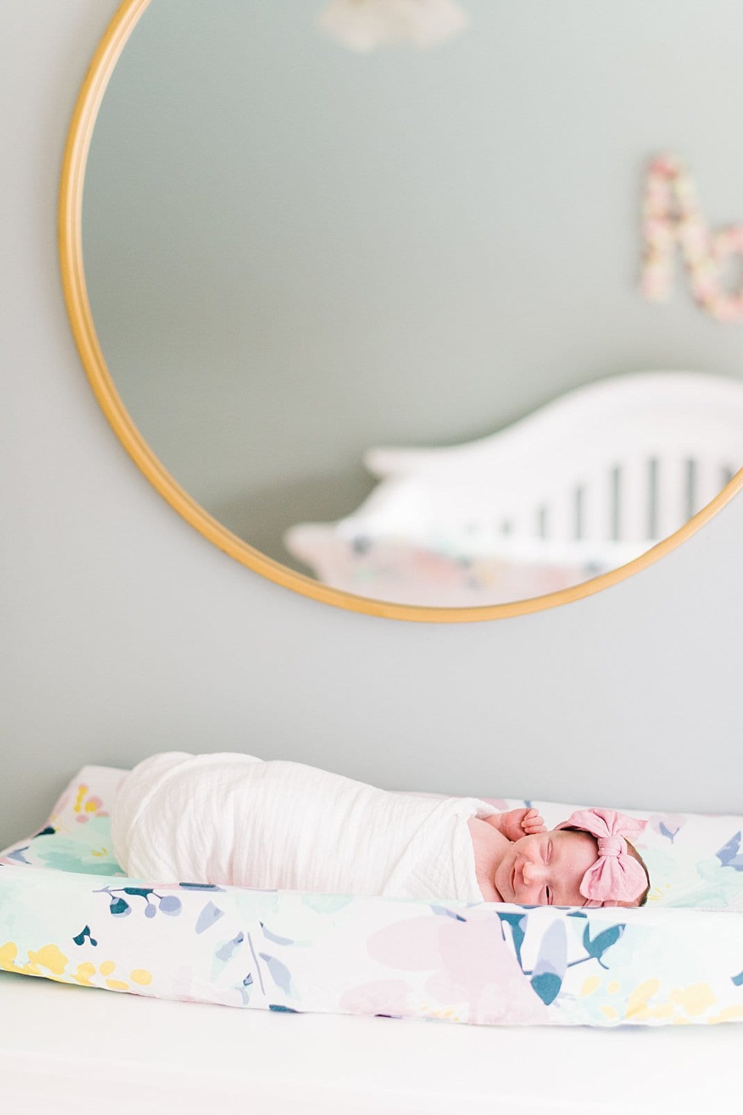 raleigh newborn laying on changing table under gold circle mirror photo