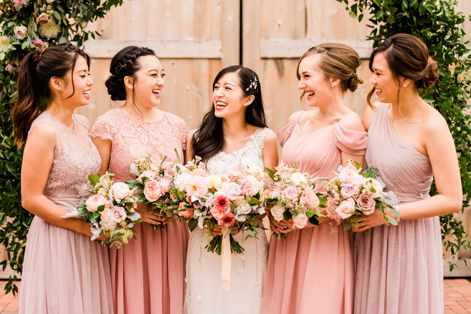 Bride laughing with bridesmaids in knee length light pink dresses photo