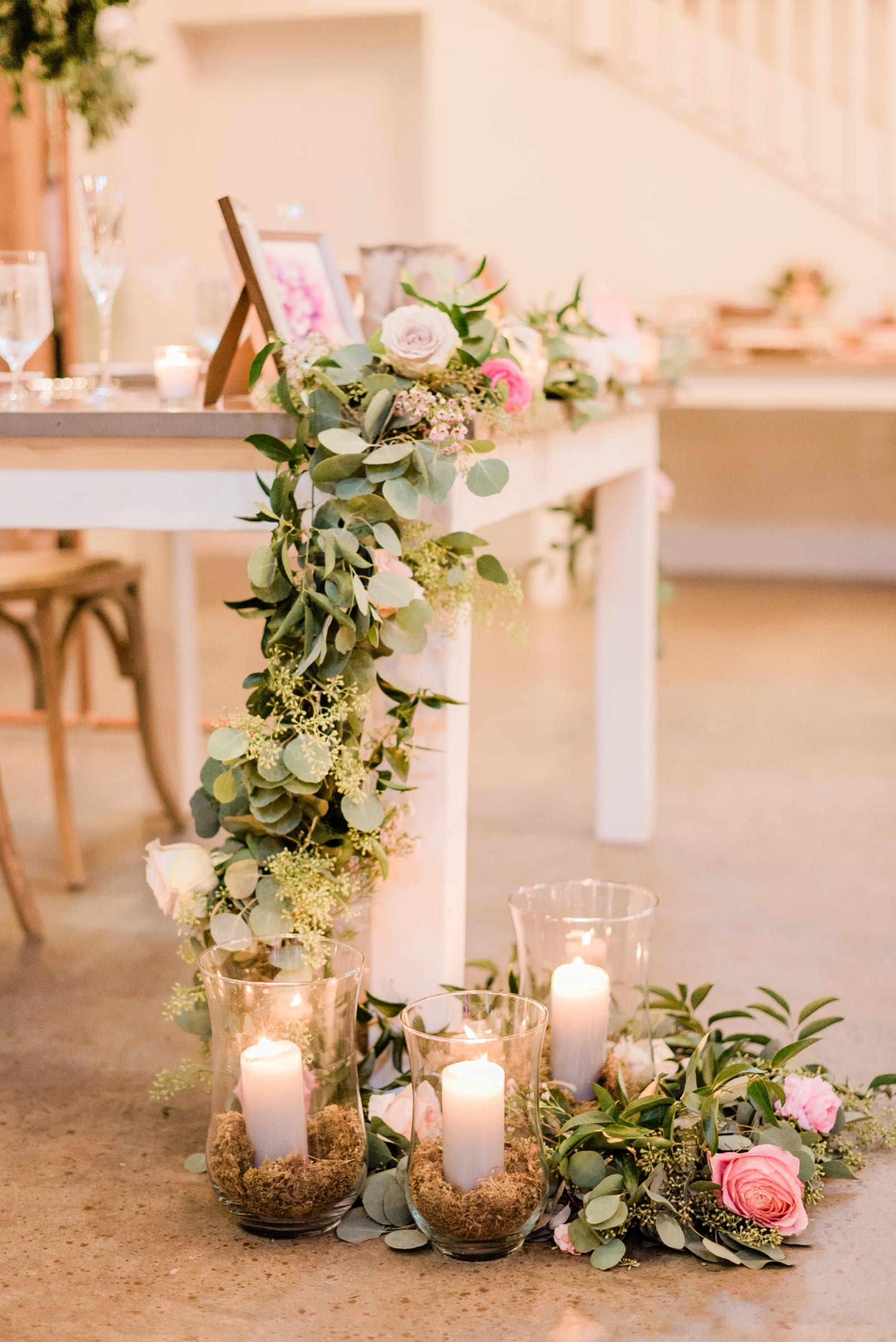 Barn of Chapel Hill greenery cascading from the sweetheart table down to the floor woven between candles photo