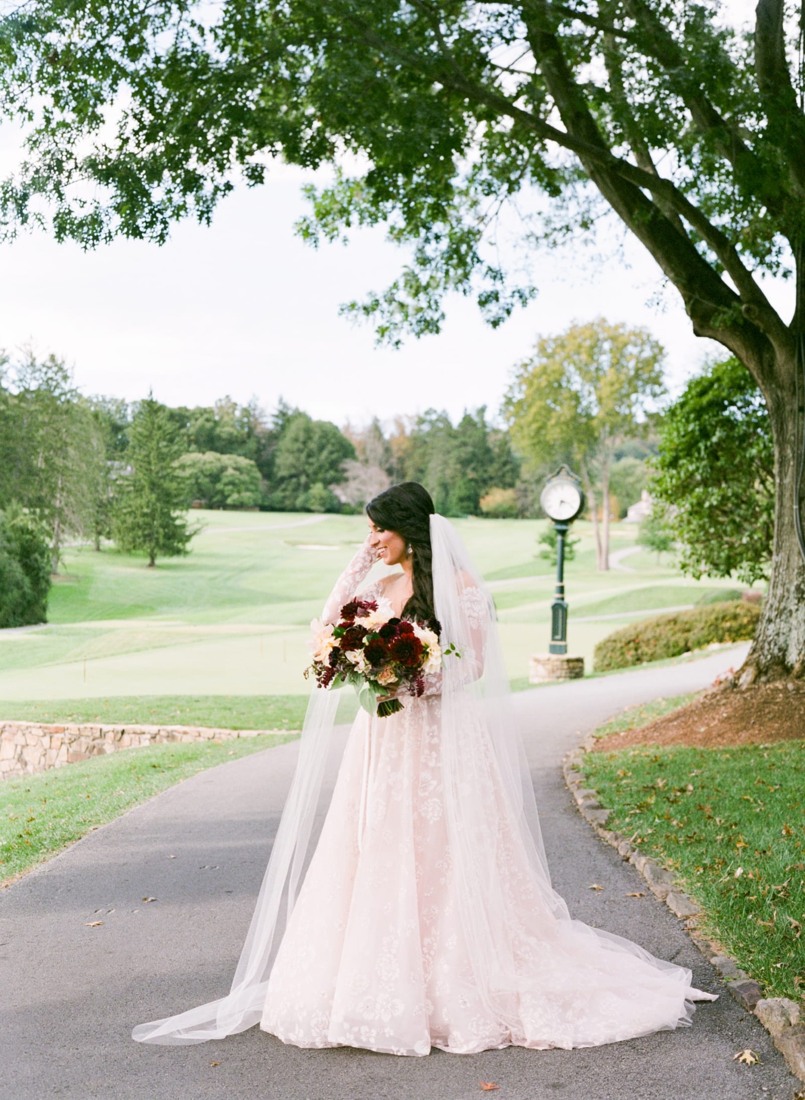 Bridal gown from Hayden Olivia Bridal with long lace sleeves and a long veil bridal portrait on a golf course photo