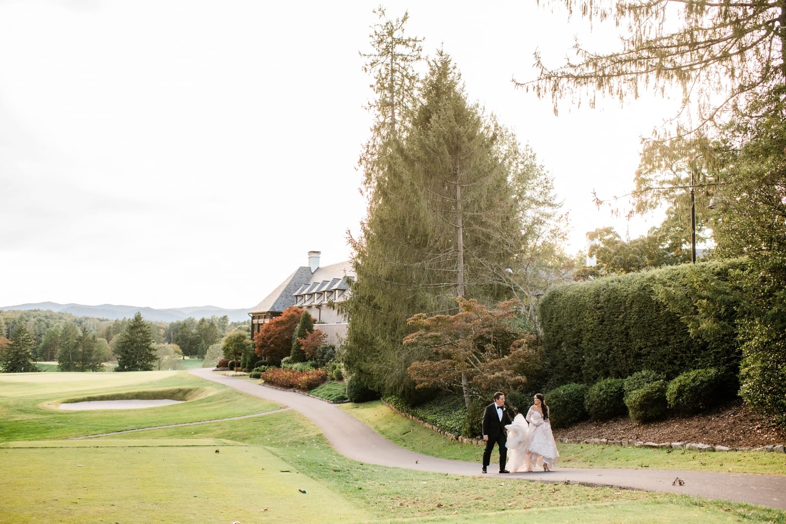 Asheville, NC bride and groom walking along golf course in front of Biltmore Forest Country Club photo