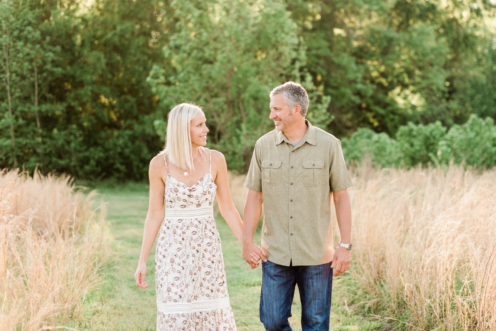 Wake Forest engagement session couple walking while holding hands next to a wheat field photo