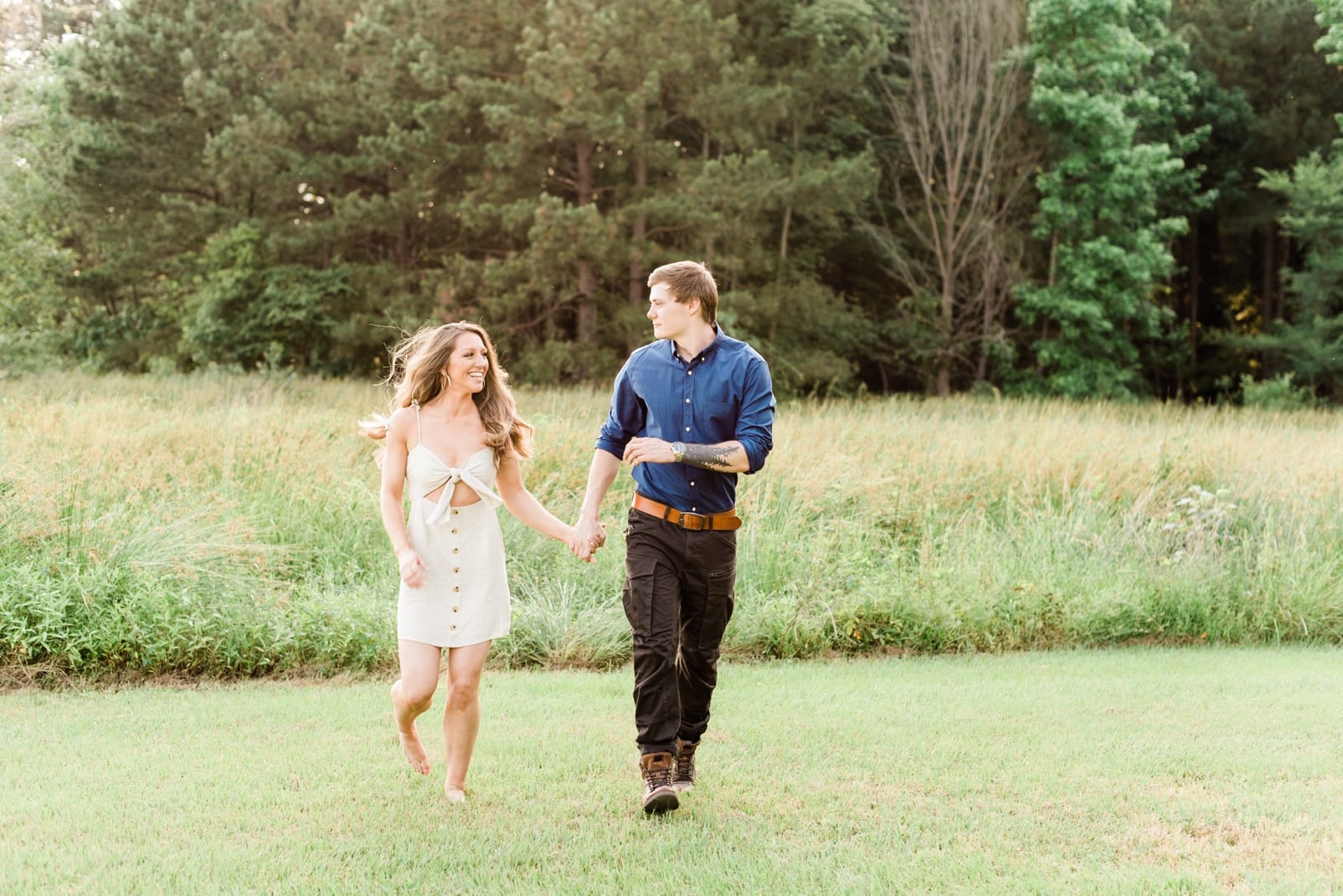 Raleigh engaged couple holding hands and running in a field photo