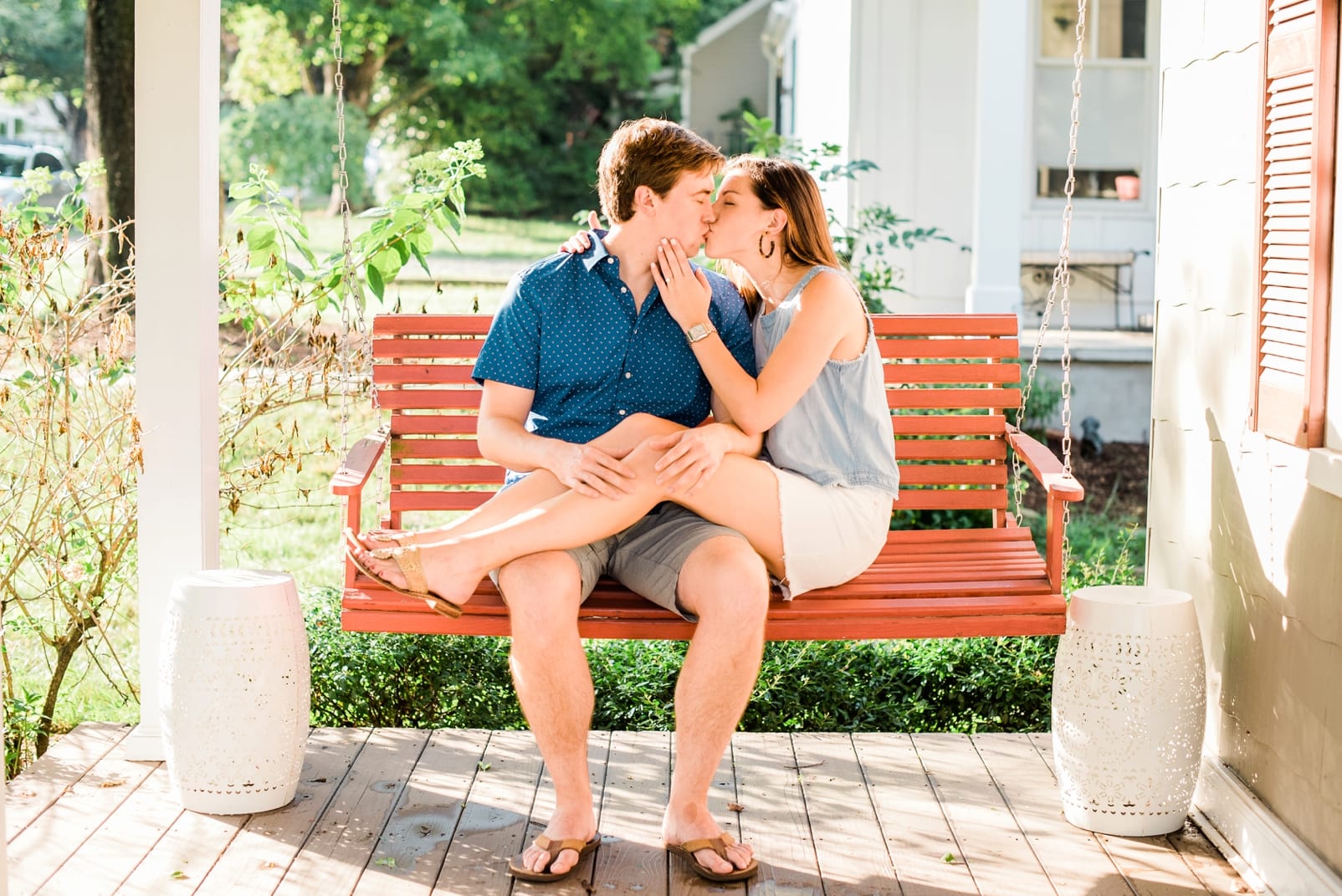 Raleigh engagement session couple sitting on front porch swing with her legs up and over his lap photo
