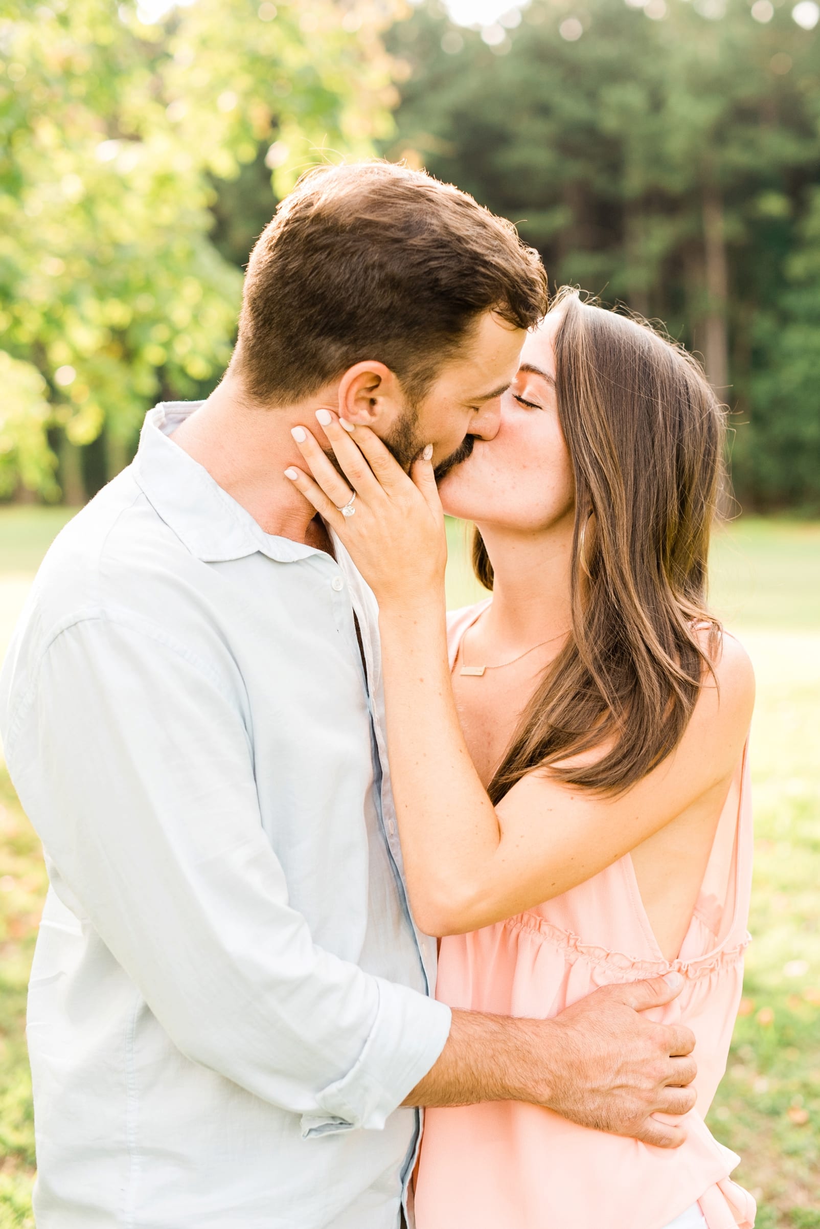 Raleigh engagement couple girl with hand on her finances cheek while they kiss photo