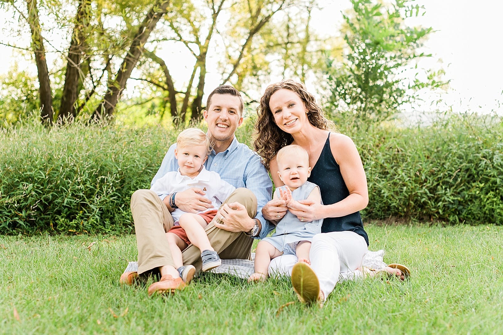 Raleigh family photographer near Raleigh family of four with two little boys sitting together in the grass photo