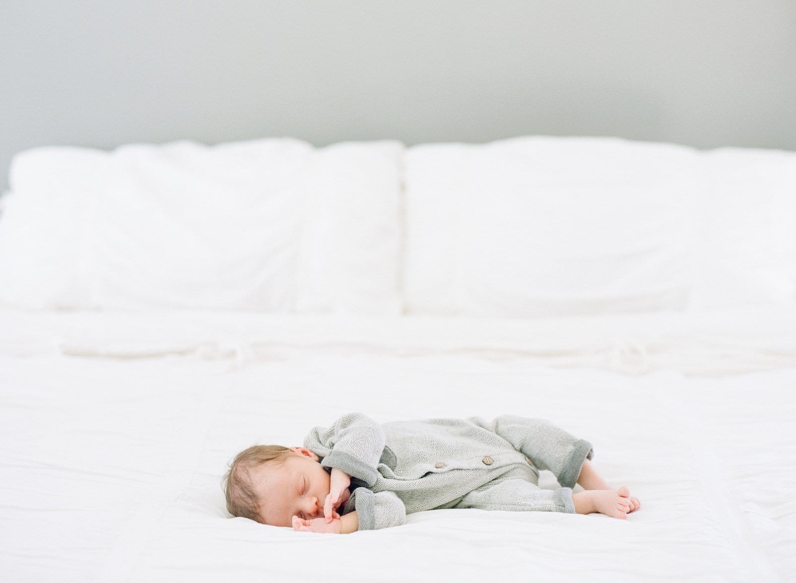Raleigh film newborn session with newborn boy laying on a white bed photo