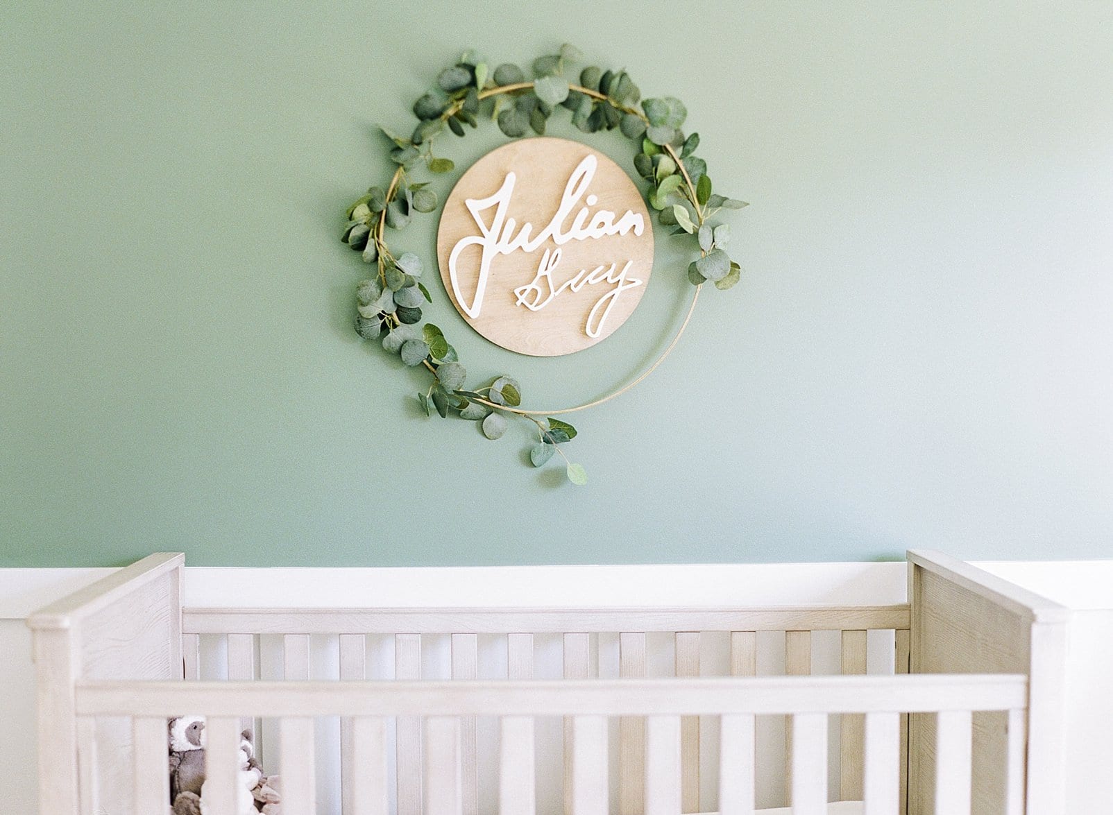 Raleigh nursery film session with a white crib and wooden circle sign hanging above it outlined in ivy photo