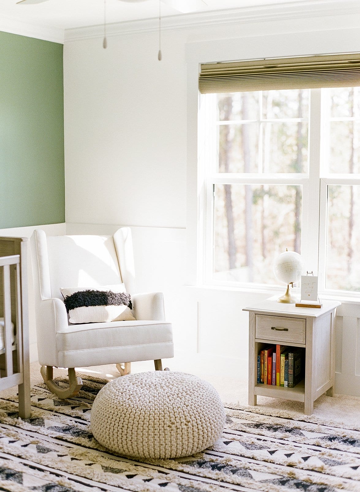 Apex newborn nursery with white rocking chair in front of a green nursery wall photo