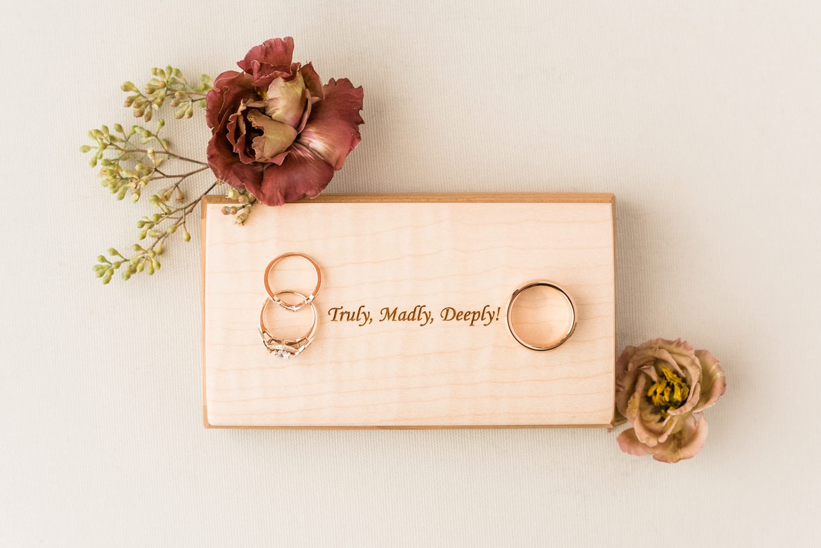 Raleigh wedding bands styled over wooden ring box carved with their names photo