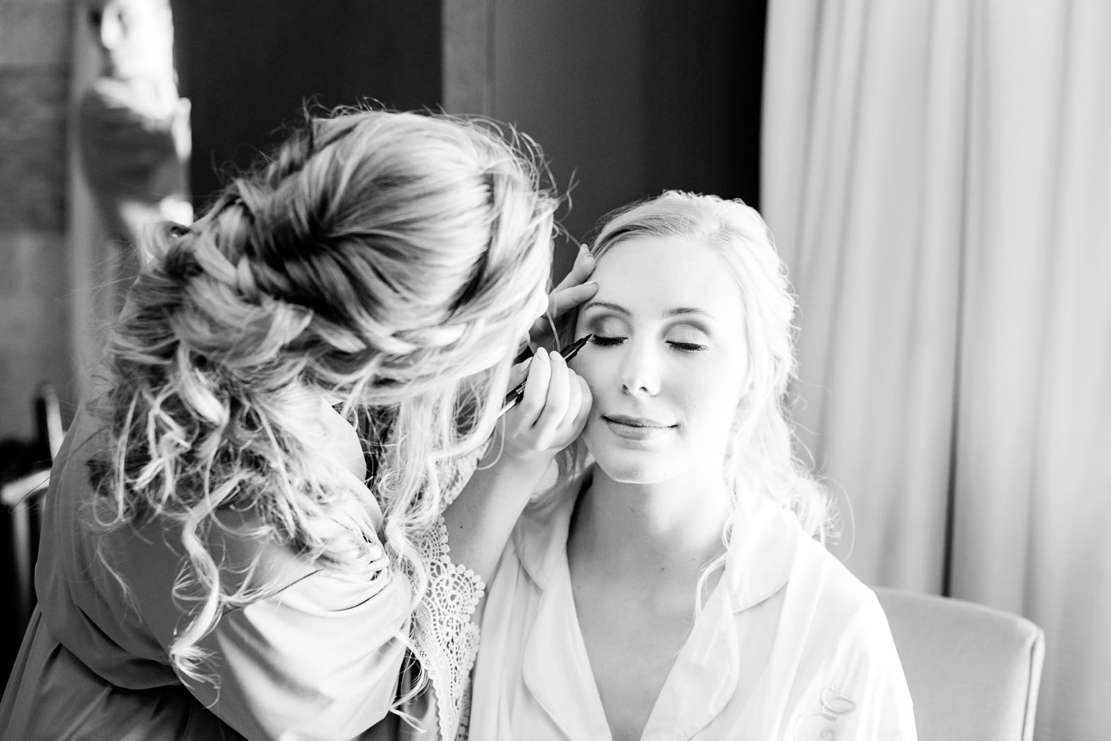 Raleigh bride getting ready with her bridesmaid putting on her makeup photo