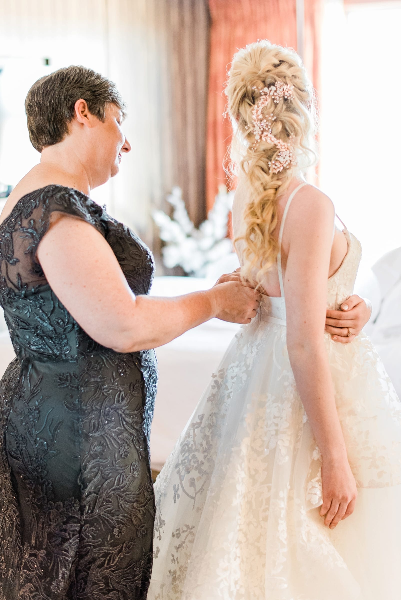 Raleigh mother getting in her wedding dress with her mother zipping up her back photo