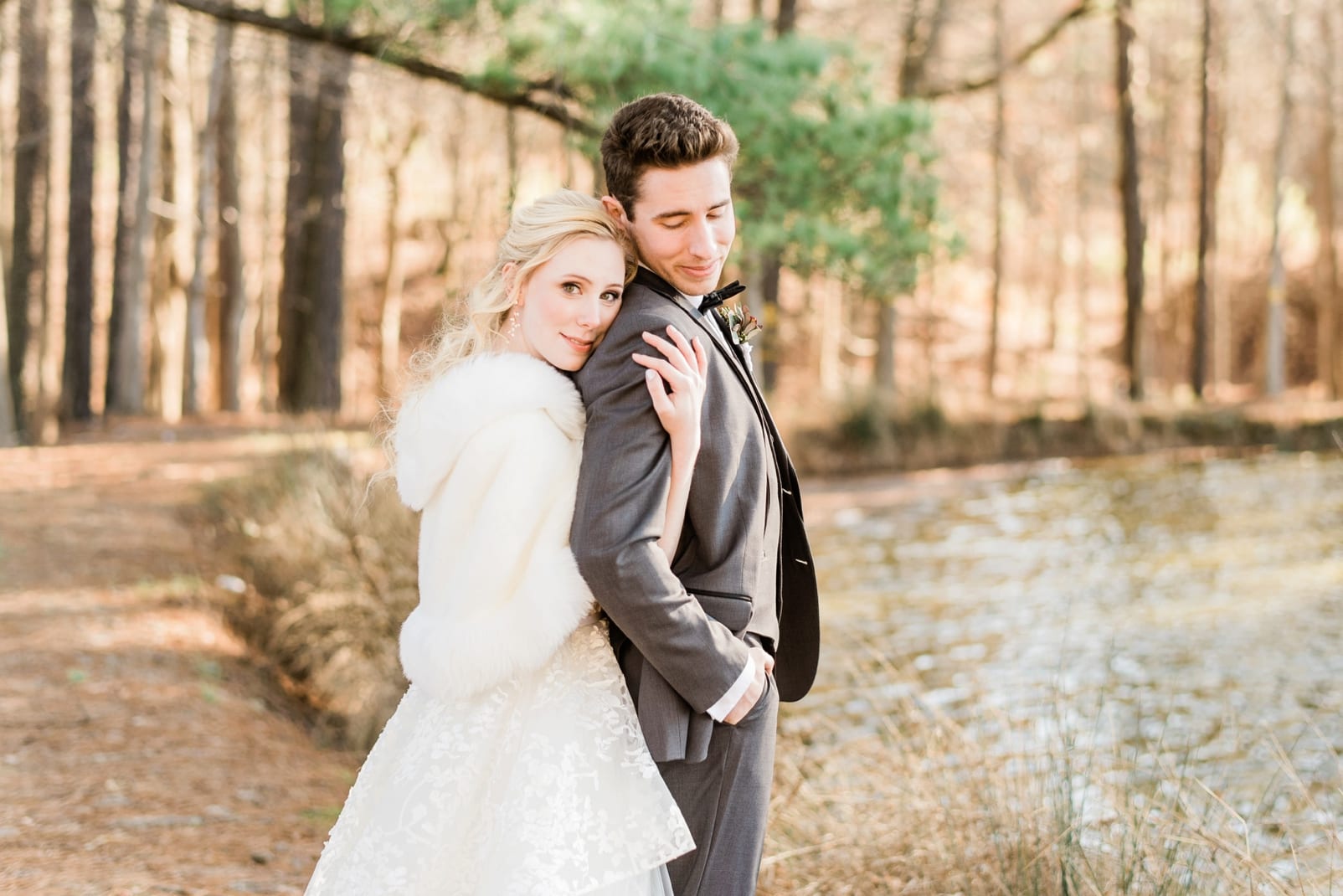 Raleigh bride snuggled into her groom from behind while standing by a pond photo