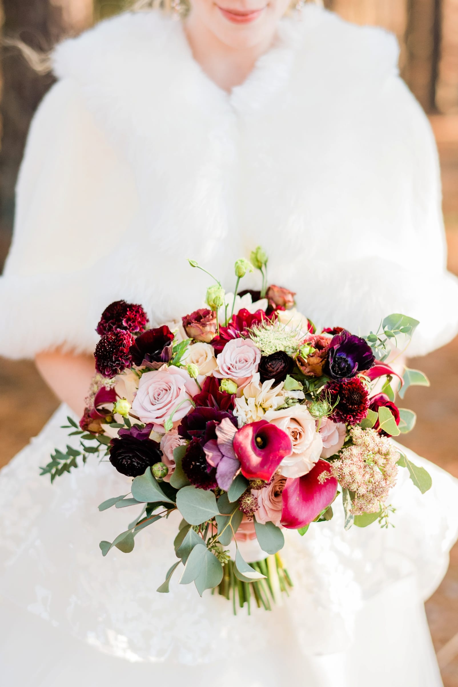Expressions of Love Florist bride holding her bridal bouquet with maroon, pink and cream flowers and sprigs of eucalyptus photo