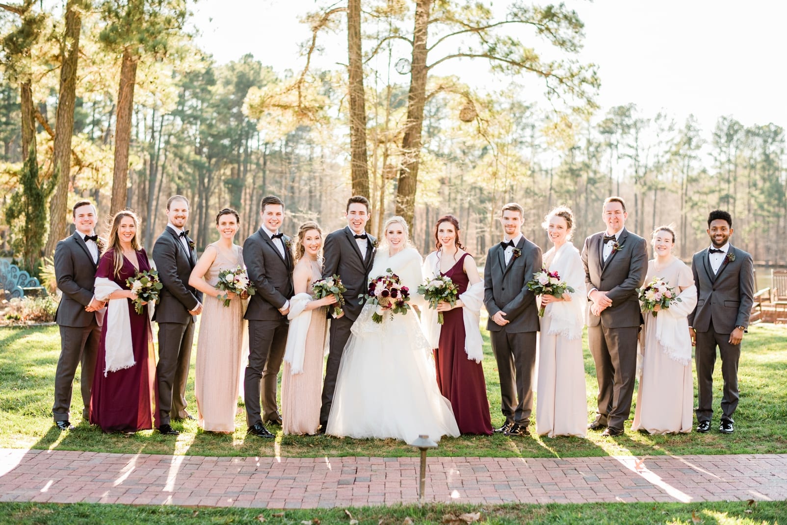 Angus Barn bride and groom with wedding party in front of brick path photo