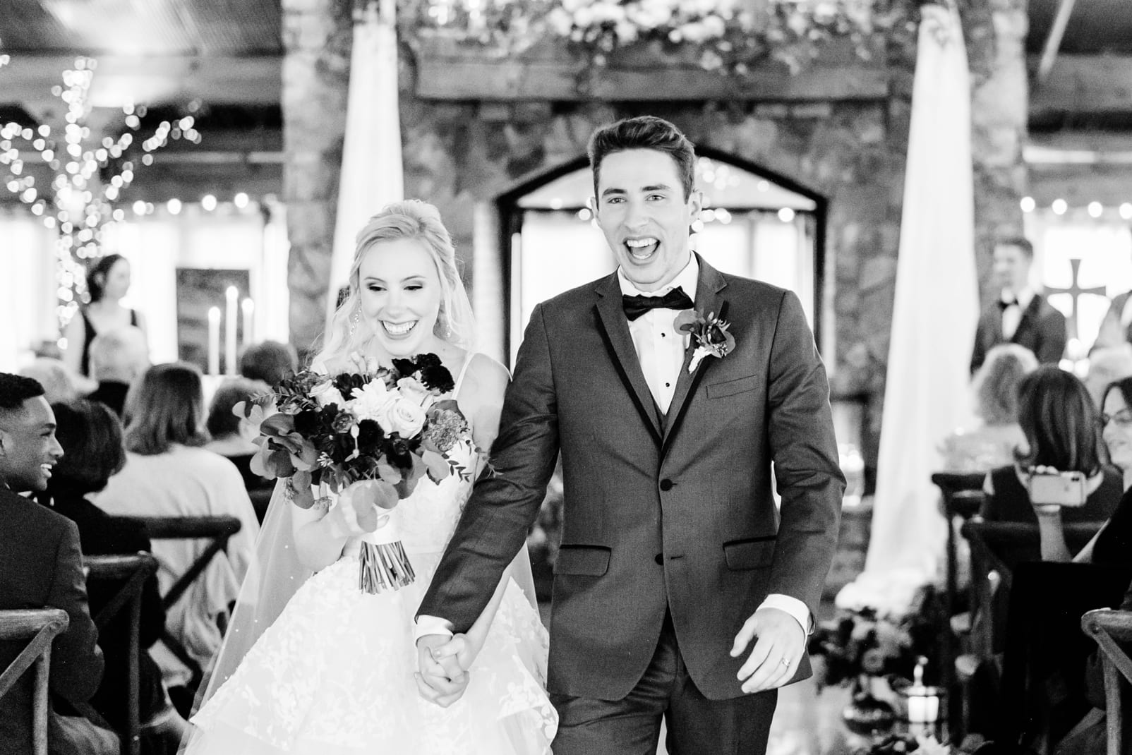 Angus Barn bride and groom holding hands coming down the aisle just married black and white photo