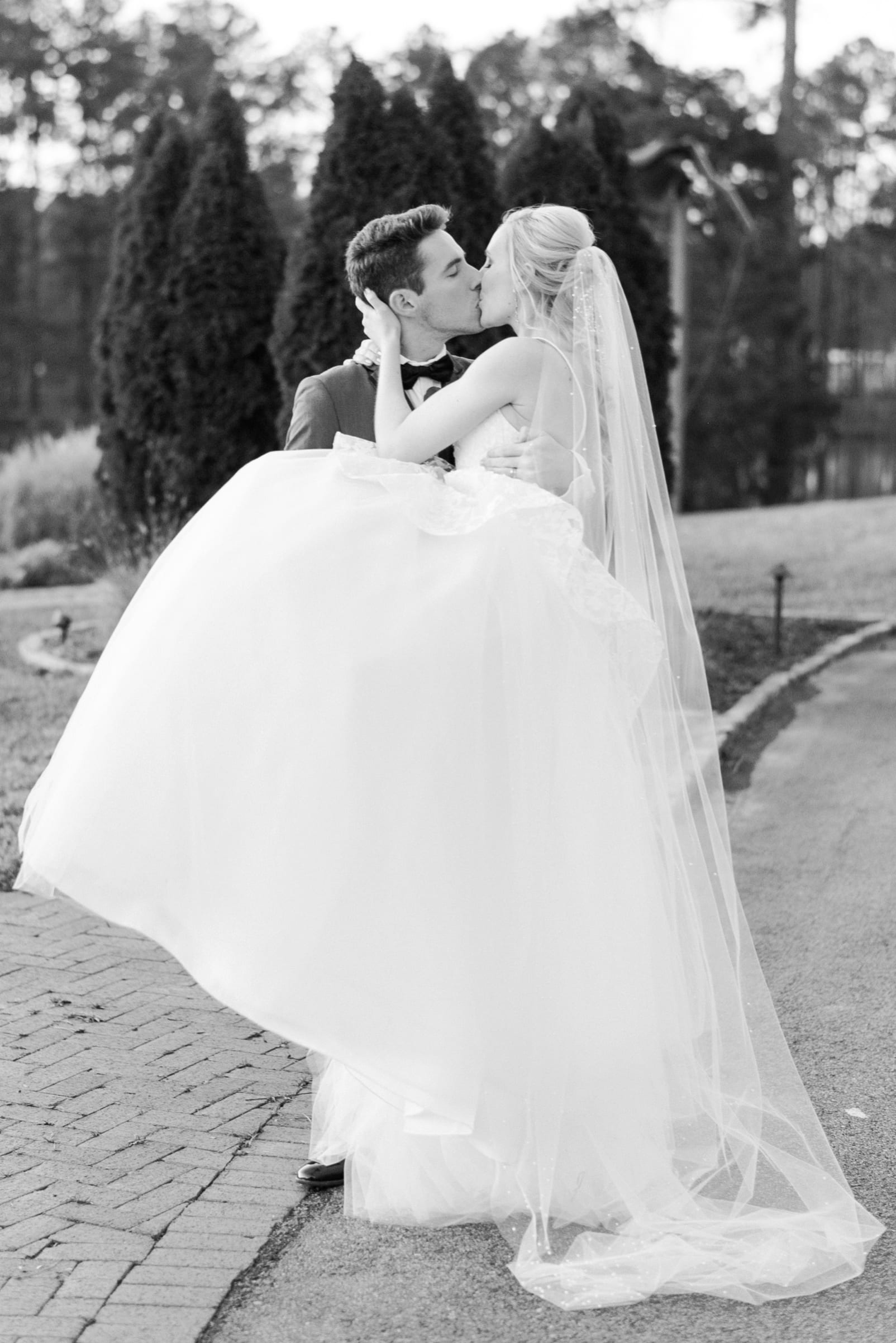 Raleigh groom holding his bride while they kiss in a black and white portrait photo