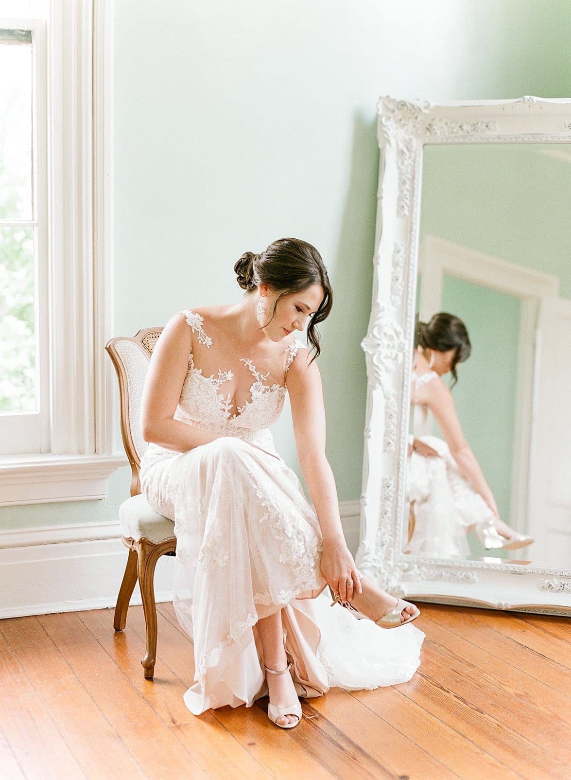 Merrimon Wynne bride sitting in front of the mirror putting her wedding shoes on photo