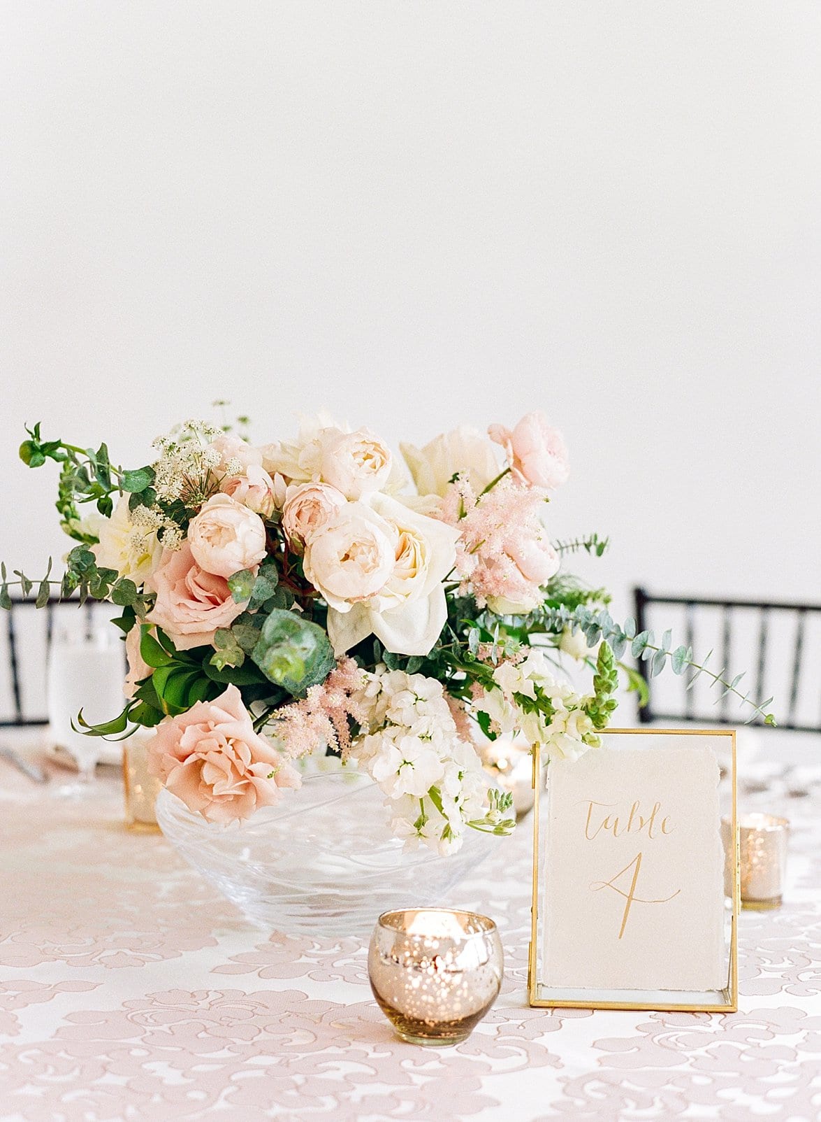 Specialties Events short floral table centerpiece with light pink and cream flowers accented with greenery photo