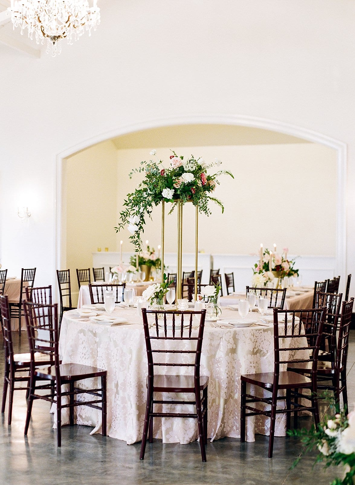 Merrimon Wynne round wedding reception tables with tall floral center piece arrangements with greenery hanging down photo