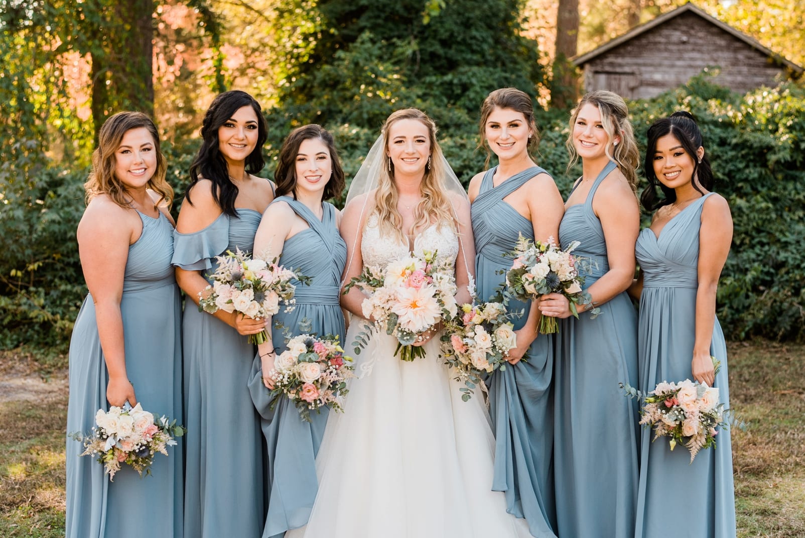 Oaks at Salem bride standing with all of her bridesmaids in long dusty blue dresses photo