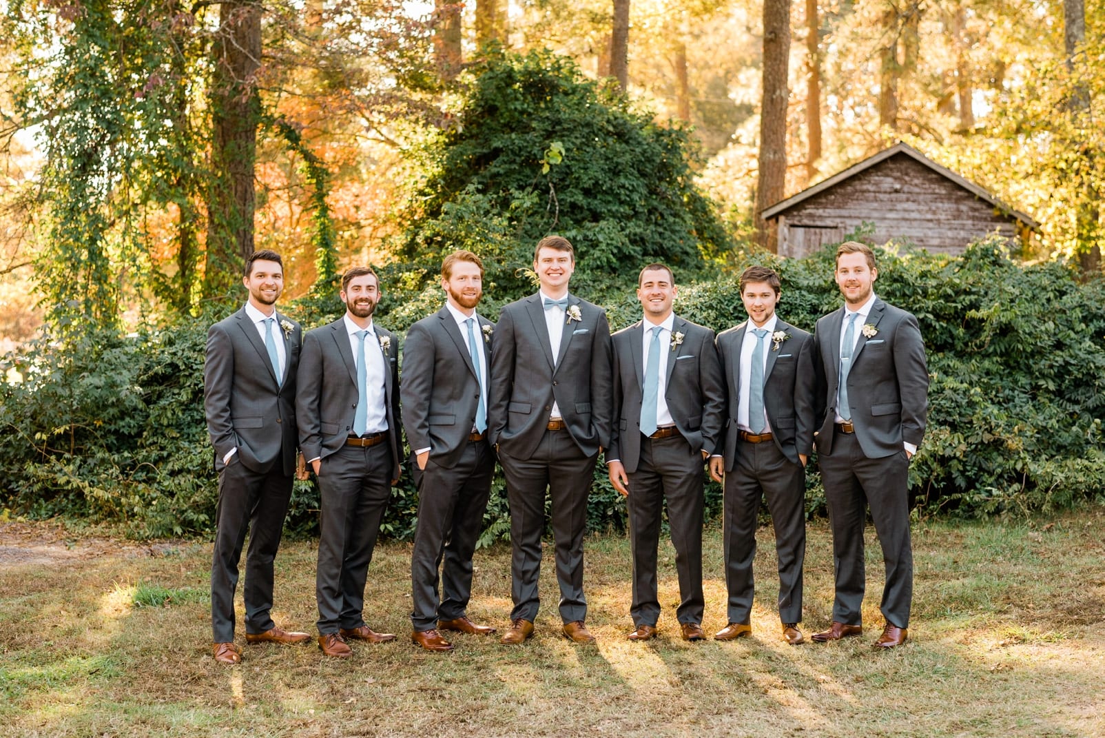 Oaks at Salem groom and groomsmen standing together in front of an old barn photo