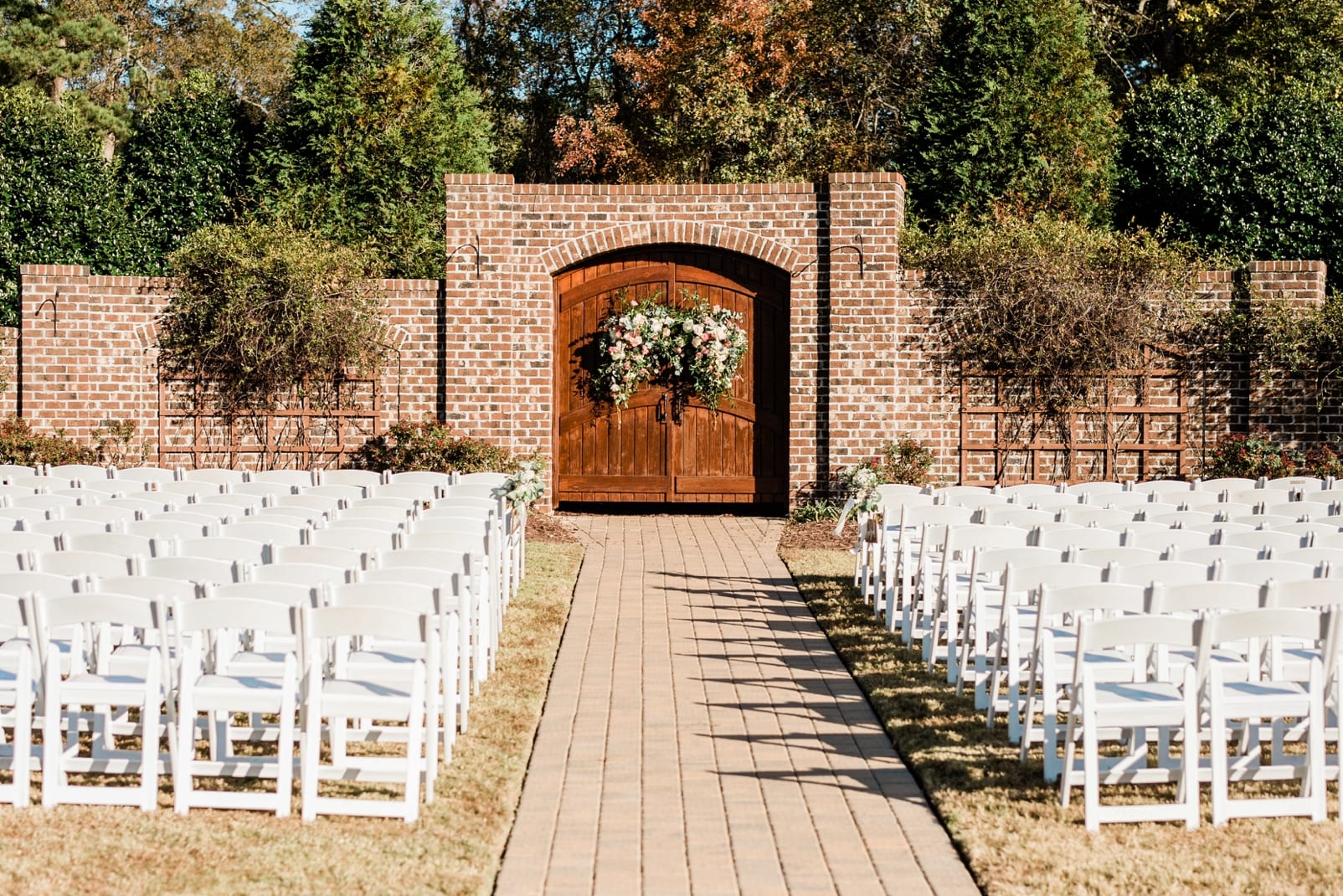 Oaks at Salem wedding ceremony in front of a red brick wall with wooden doors in the center photo