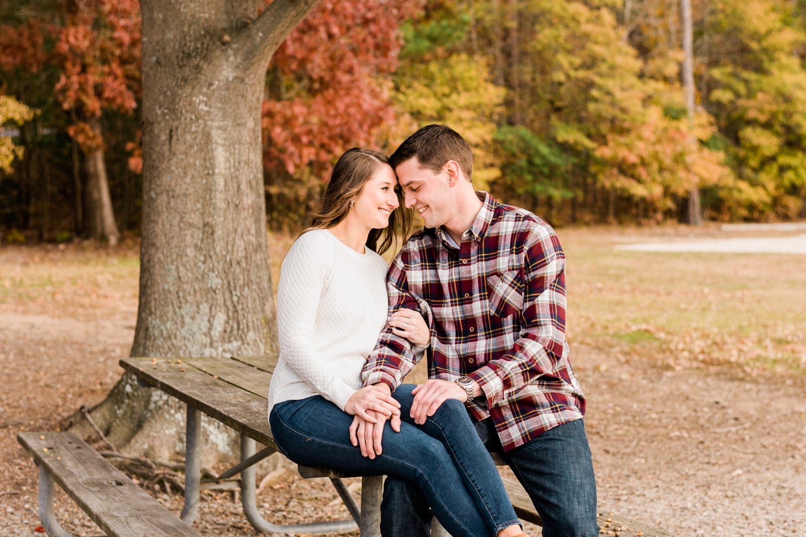 Morrisville couple sitting on a picnic table during their engagement session photo