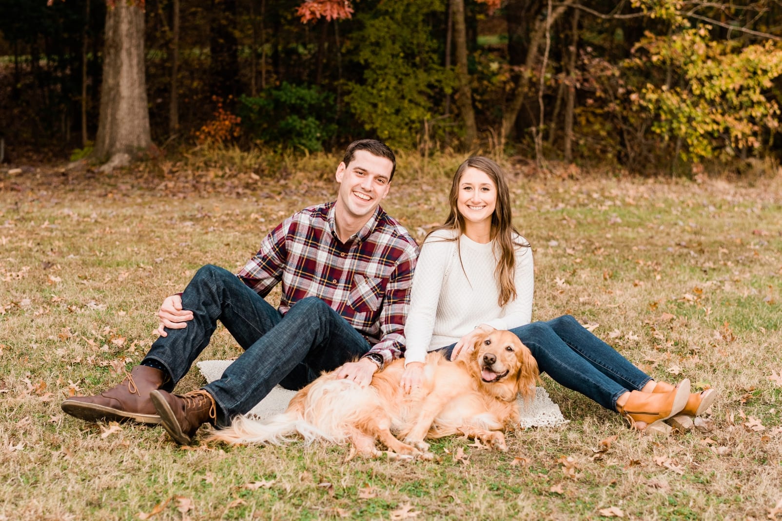 Raleigh couple sitting in the grass with their dog in between them photo