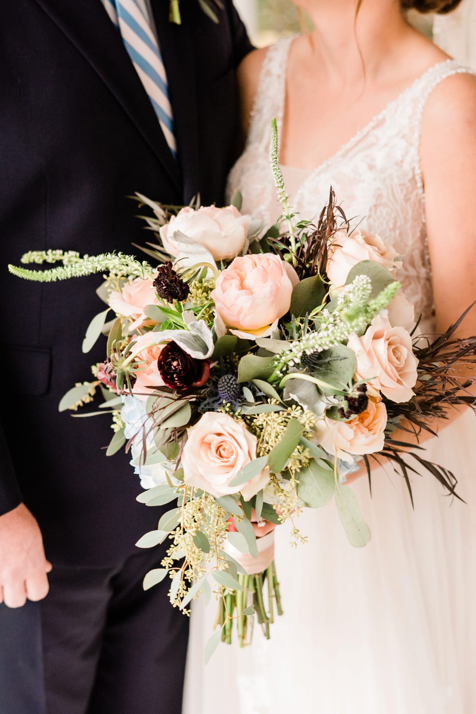 University Florist bridal bouquet with deep purple, peach and cream flowers and sprigs of light greenery photo