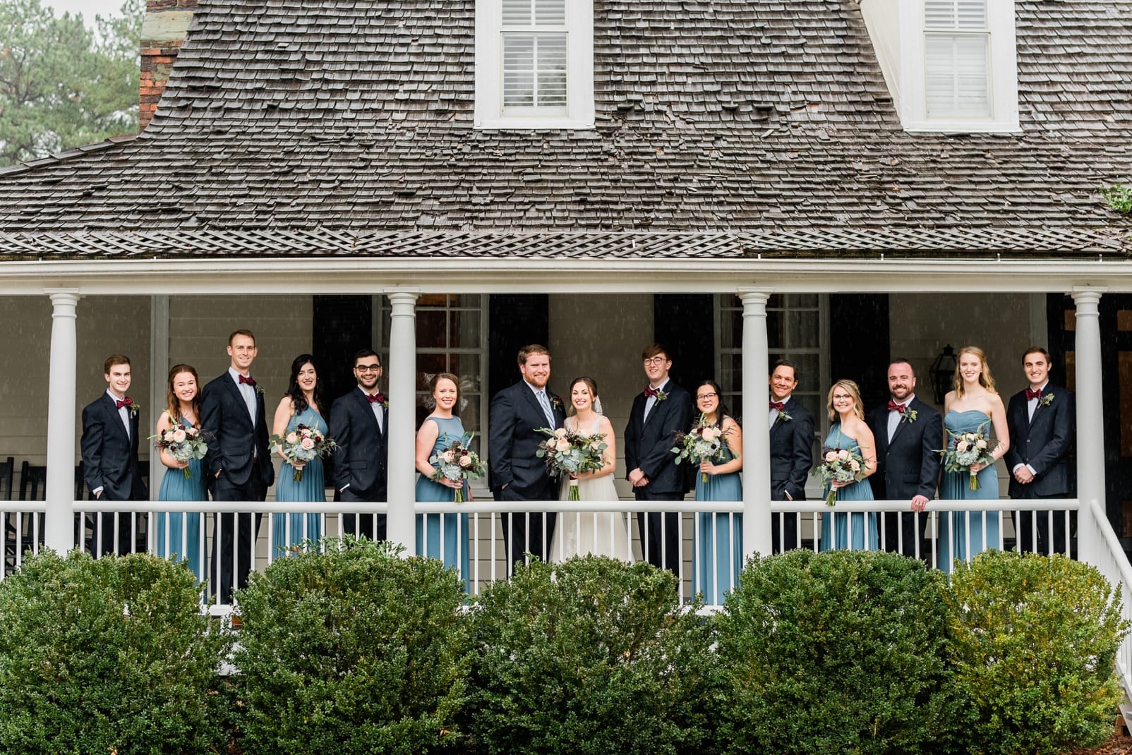 Sutherland Estate wedding party with the bride and groom standing across the covered front porch photo