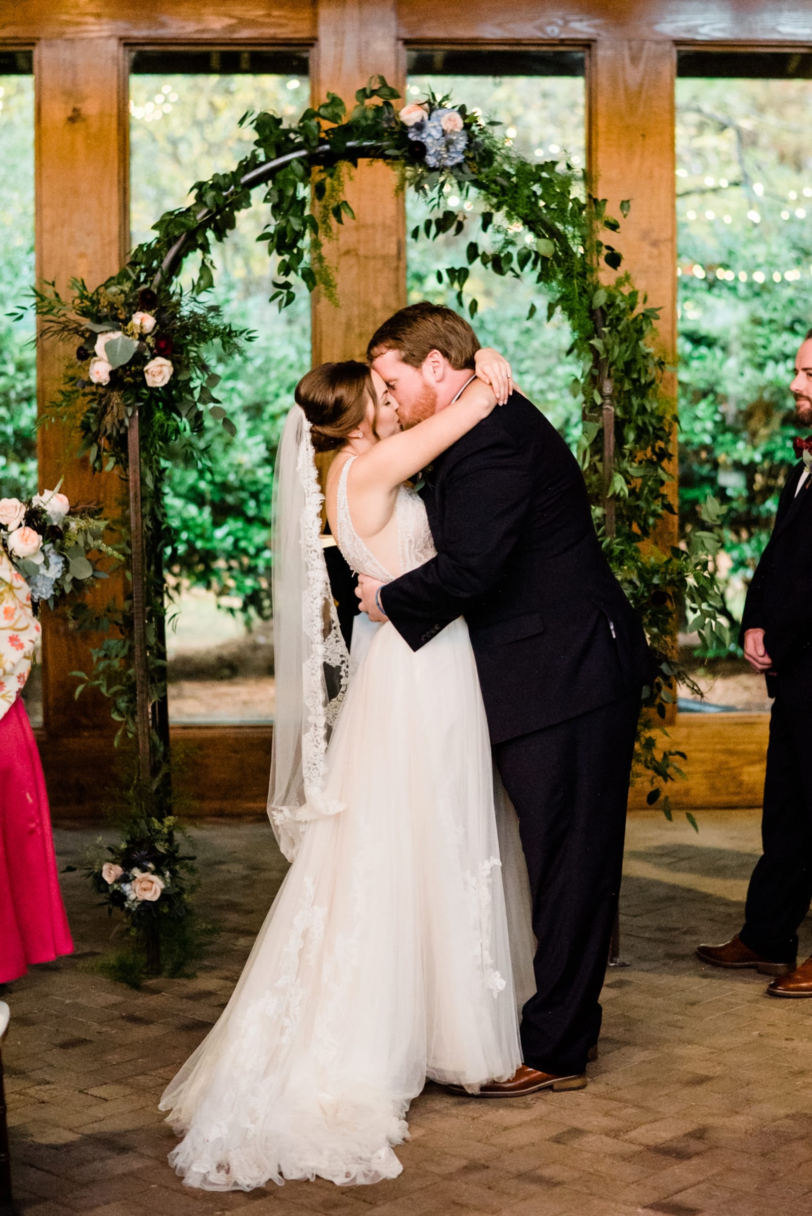 Sutherland Estate indoor wedding ceremony bride and groom first kiss under floral arch photo