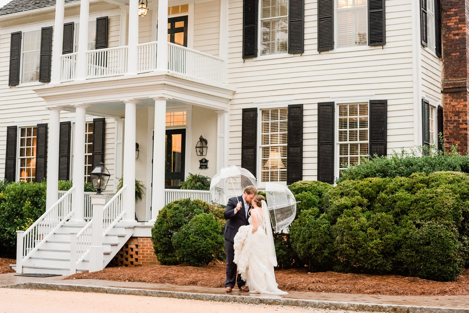 Wake Forest bride and groom kissing in the rain in front of the Sutherland Estate photo