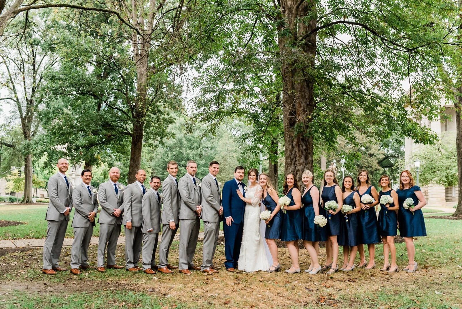 The North Carolina Capital Grounds wedding party picture with groomsmen in gray suits and bridesmaids in navy blue dresses photo