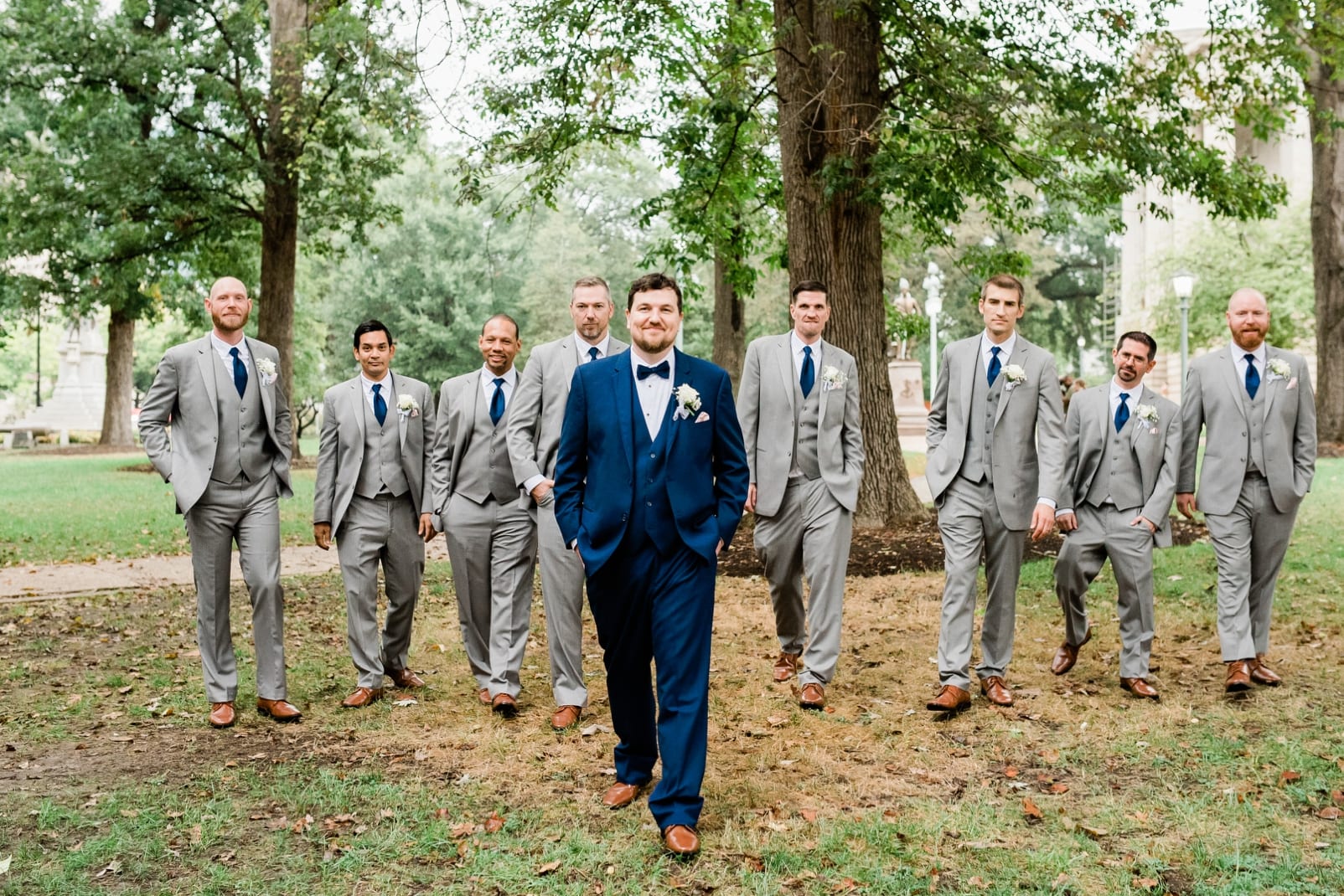 Raleigh Capital grounds groom in navy blue tux walking in front of his groomsmen in gray suits photo
