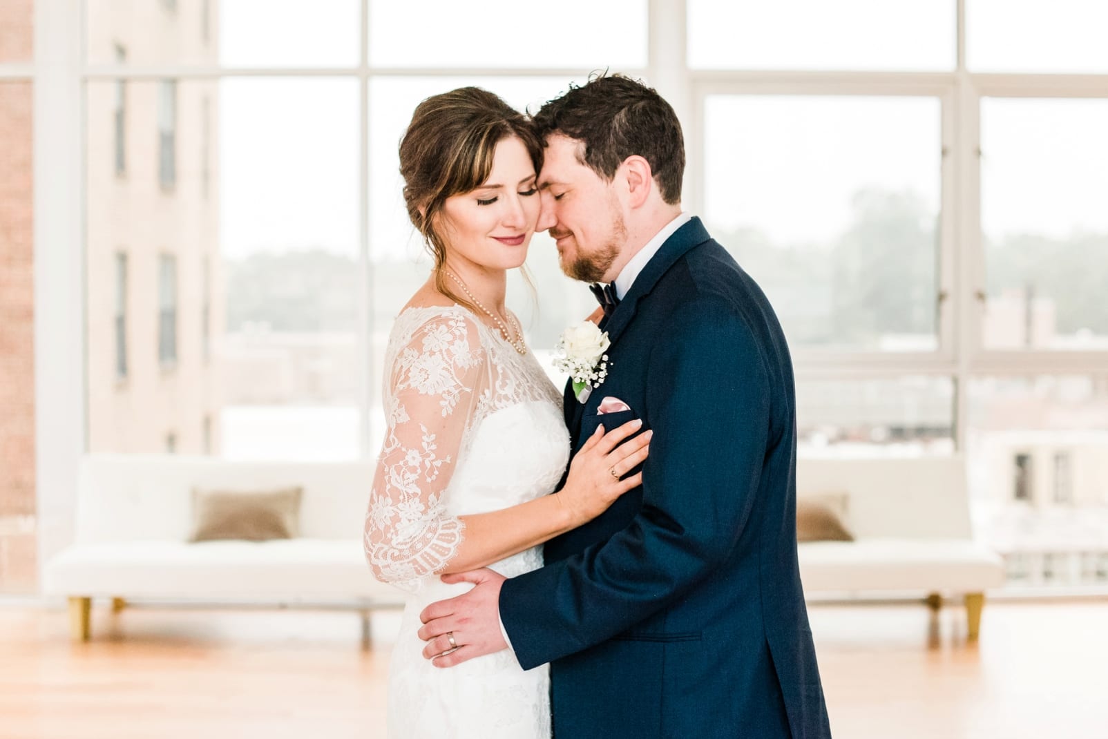 The Glass Box bride and groom snuggled together in front of all glass windows photo