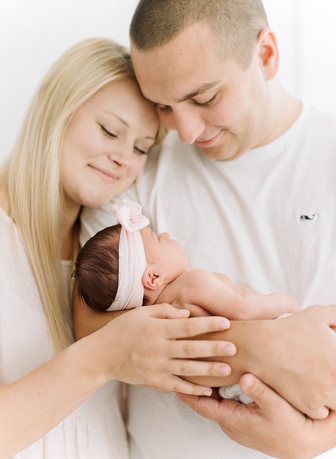 Film newborn pictures with father holding his newborn daughter while the mother snuggles in photo