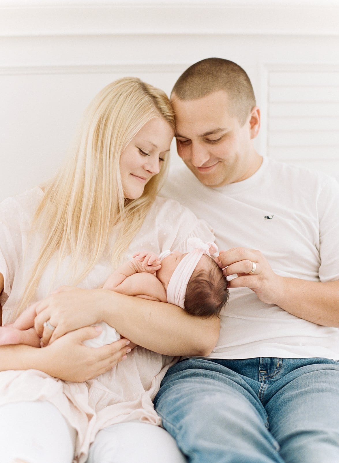 Raleigh newborn girl being held by her mother and father sitting on their bed photo