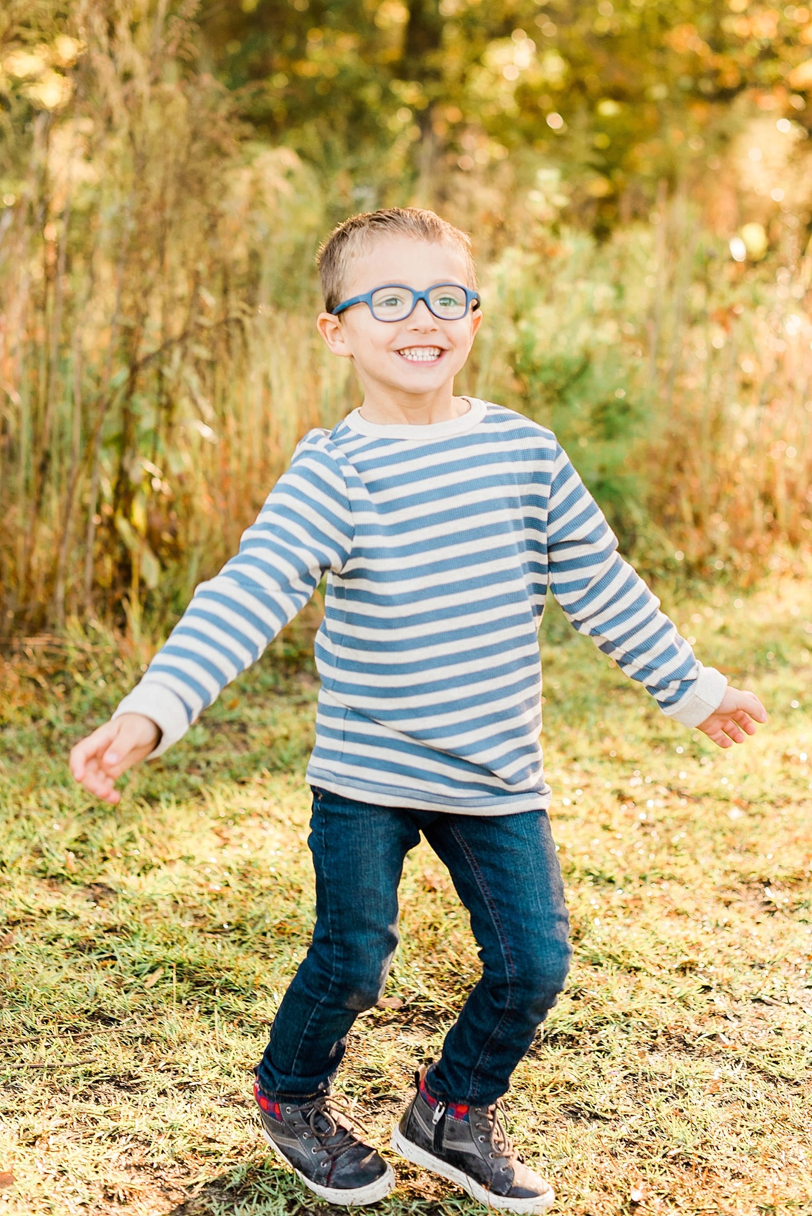 Raleigh 4 year old boy in a long sleeve striped shirt playing on a grass road photo