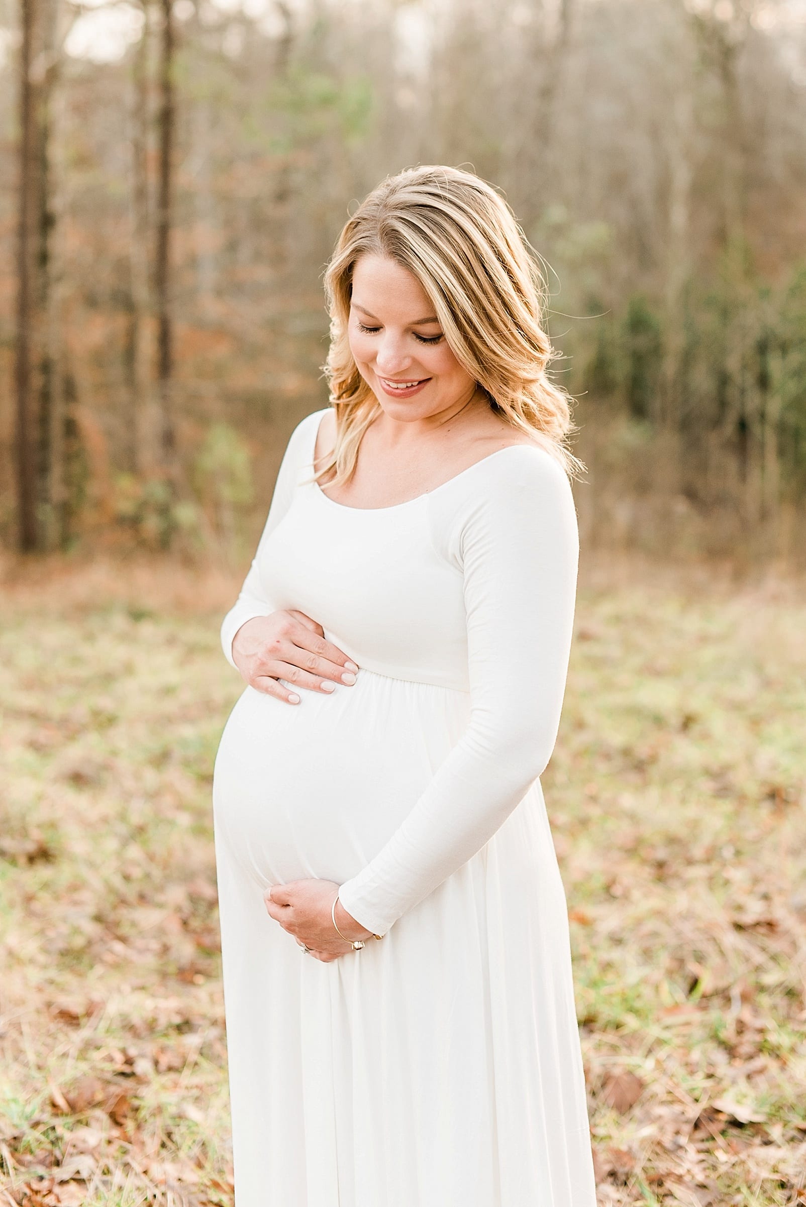 Raleigh maternity session mother in a long cream dress looking down at her belly photo
